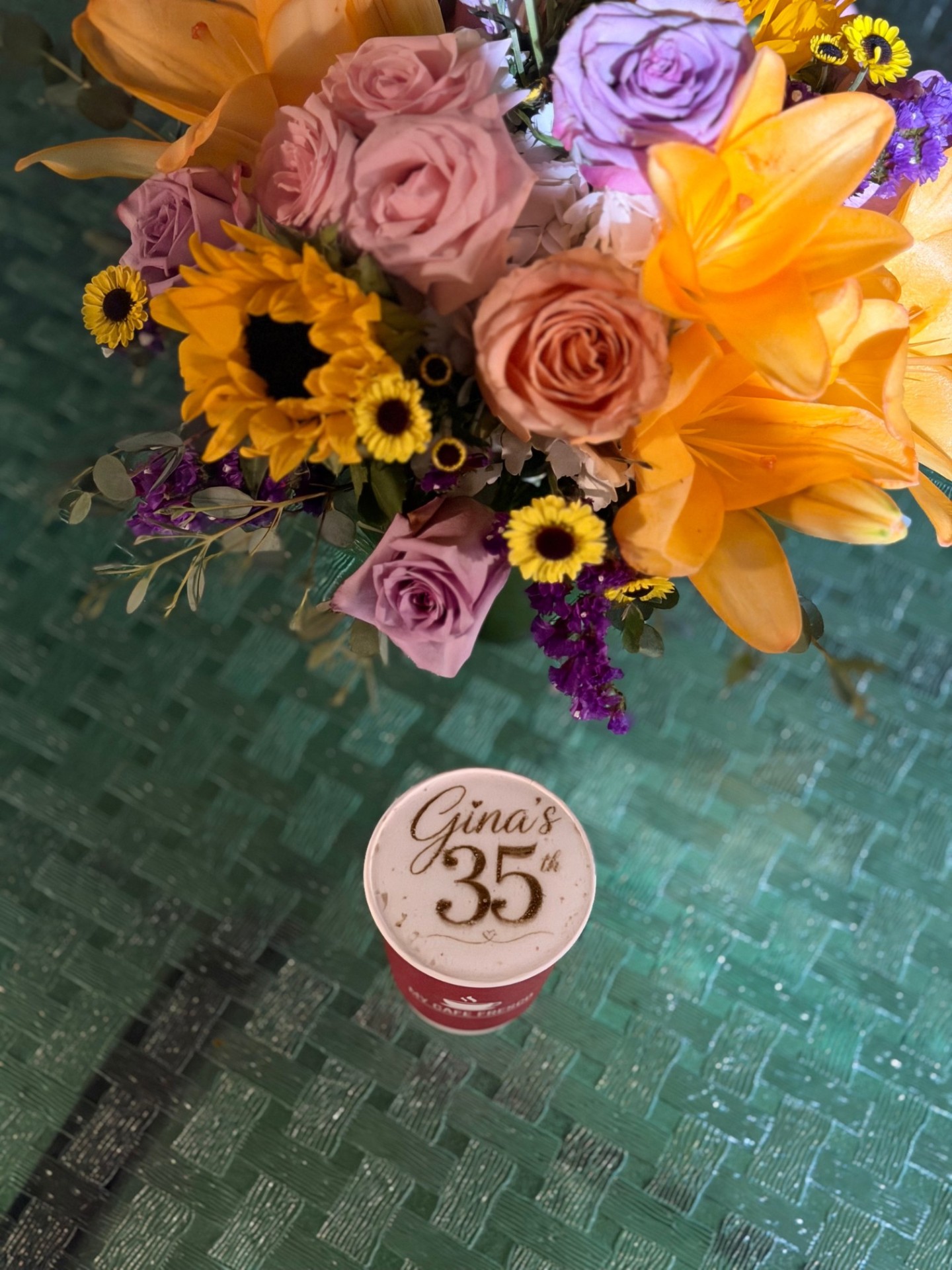 Custom birthday photo latte next to a floral arrangement