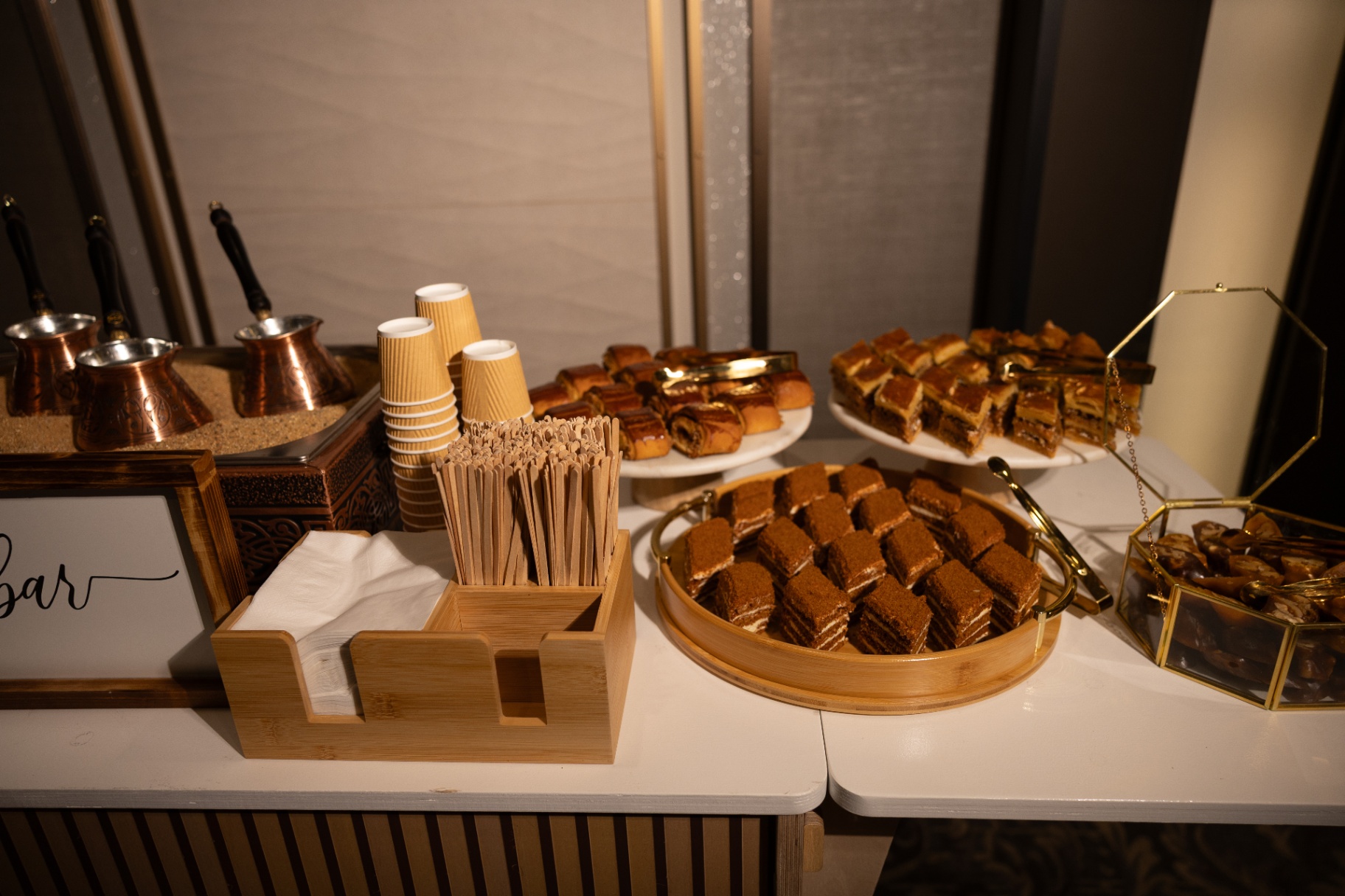 Armenian coffee station with copper jazzves in sand and trays of gata, honey cake, and stuffed dates