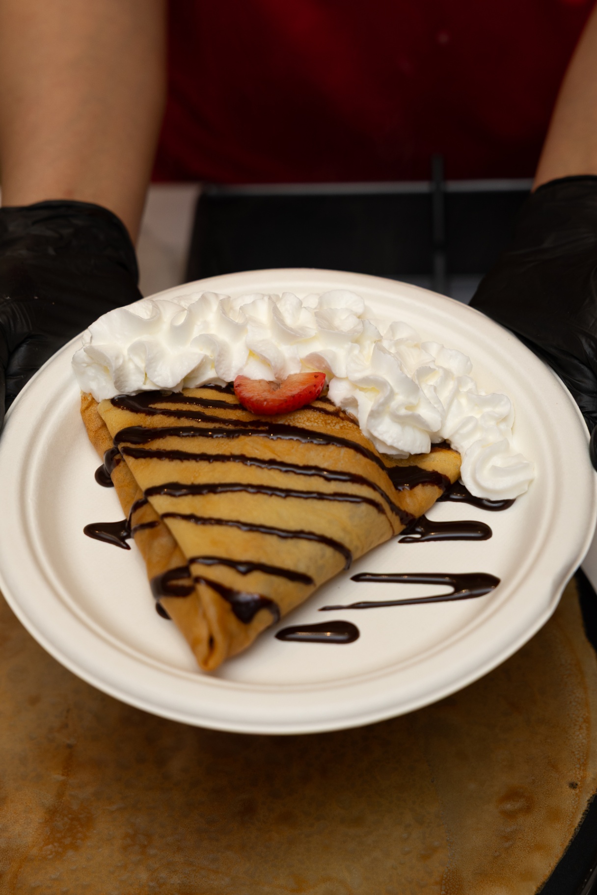 Plated crepe with strawberry, chocolate, and whipped cream