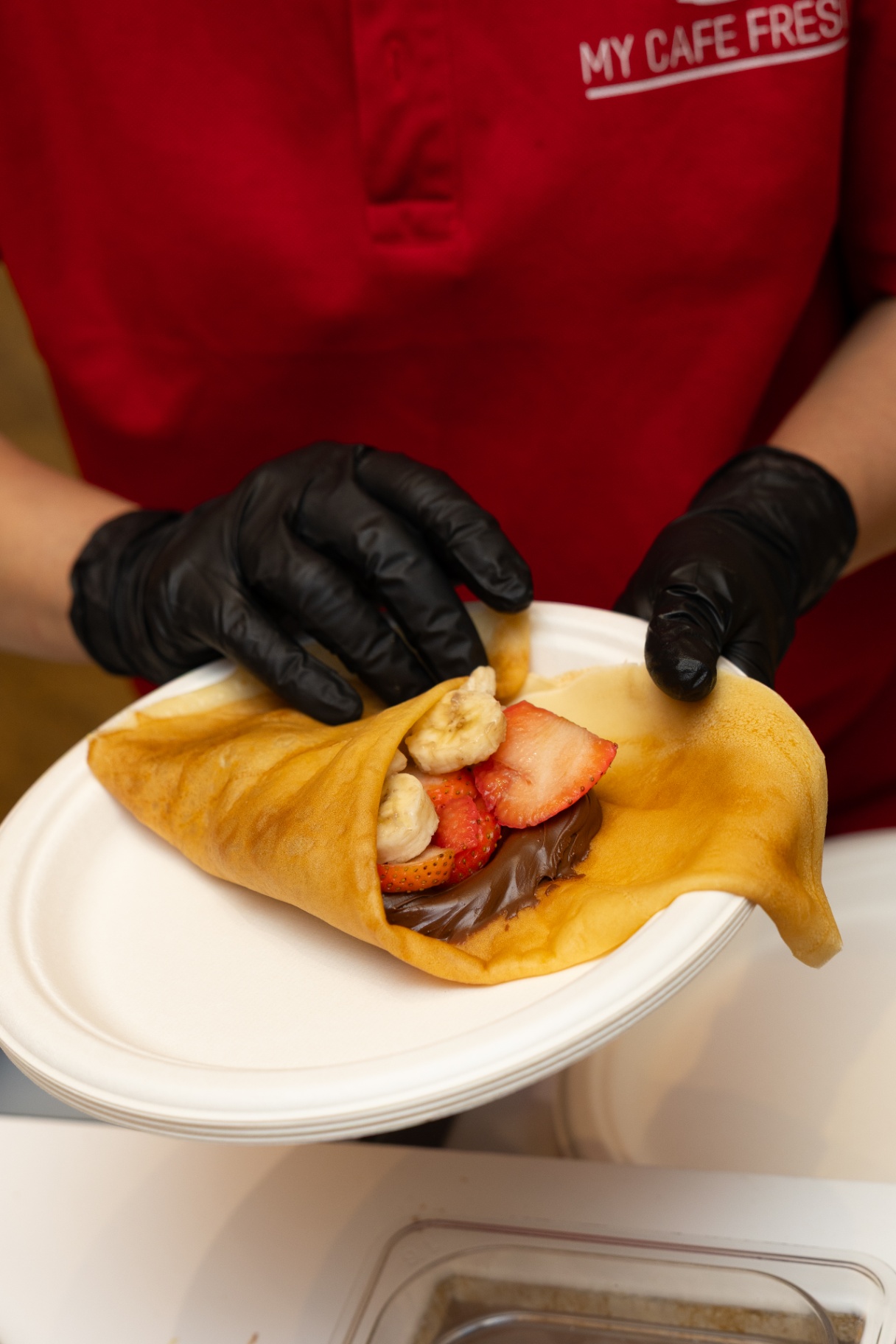 Nutella crepe with fresh strawberries and banana being folded