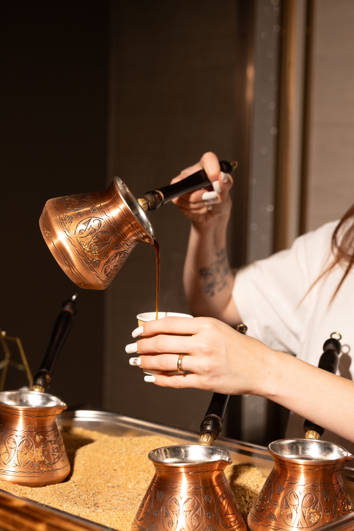 Barista pouring Armenian coffee from an engraved copper jazzve into a cup