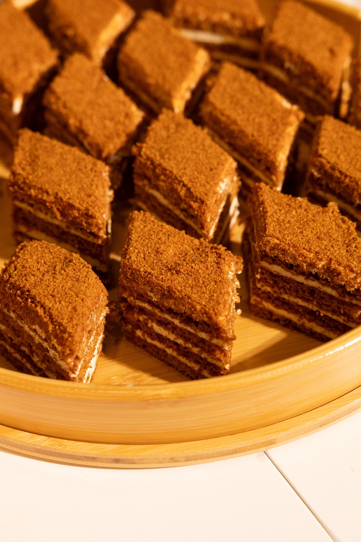 Layered Armenian honey cake squares plated on a wooden tray