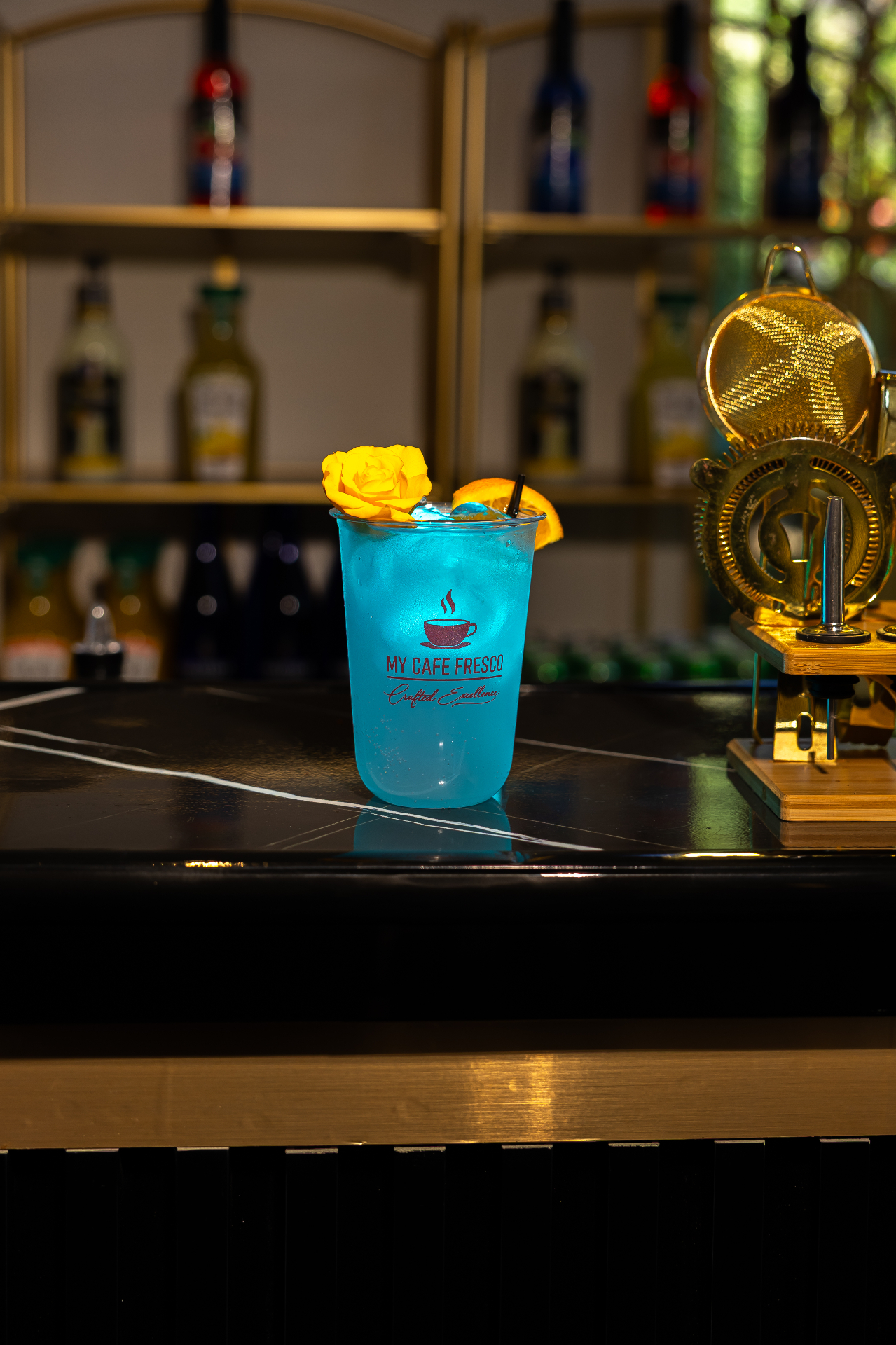 Blue mocktail with yellow rose garnish on a marble bar