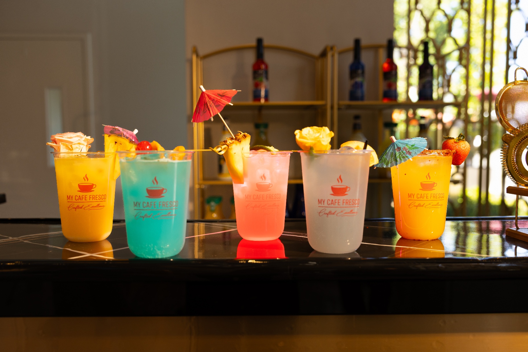 Lineup of five branded My Cafe Fresco mocktails on a marble bar