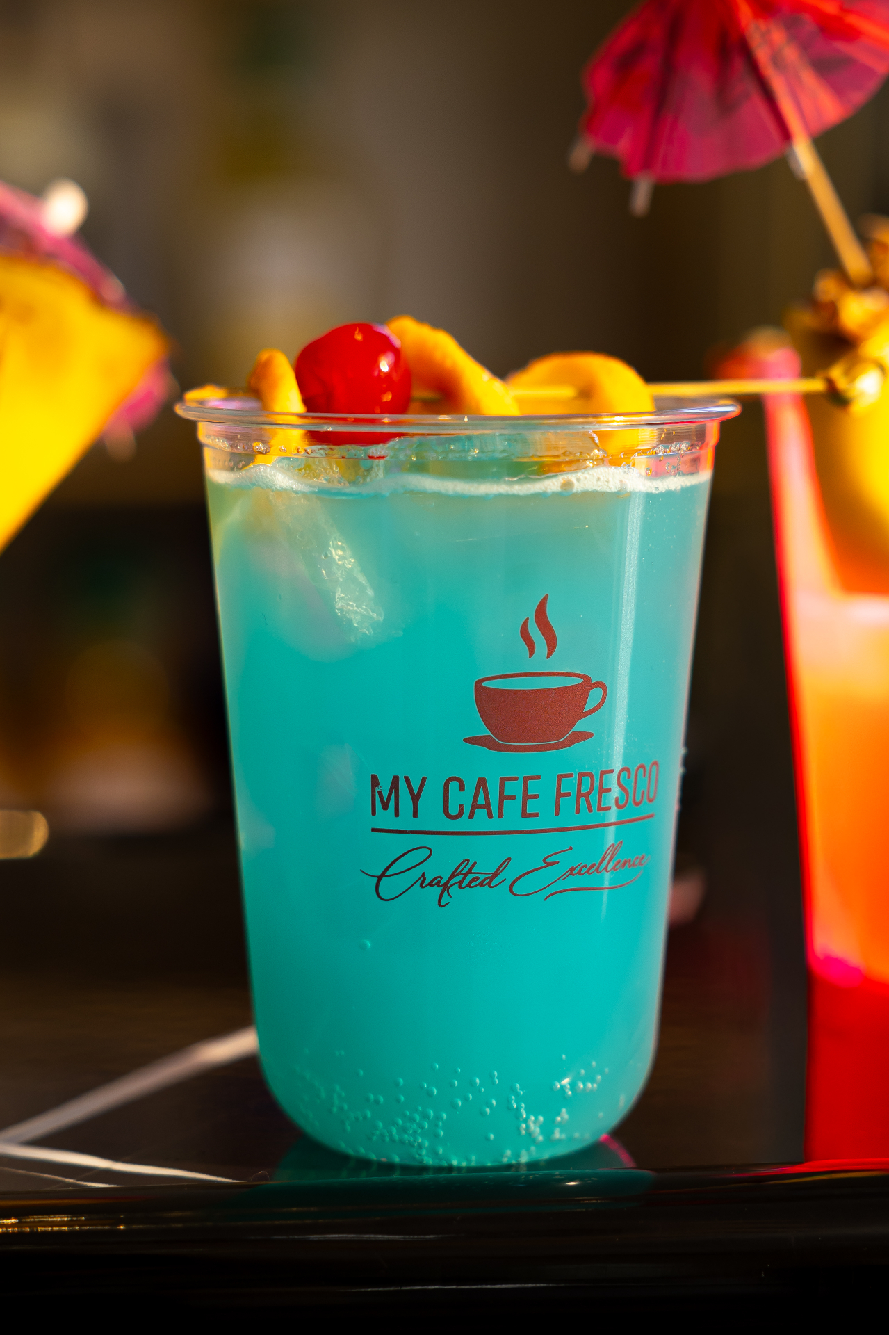 Close-up of a branded blue mocktail with cherry garnish