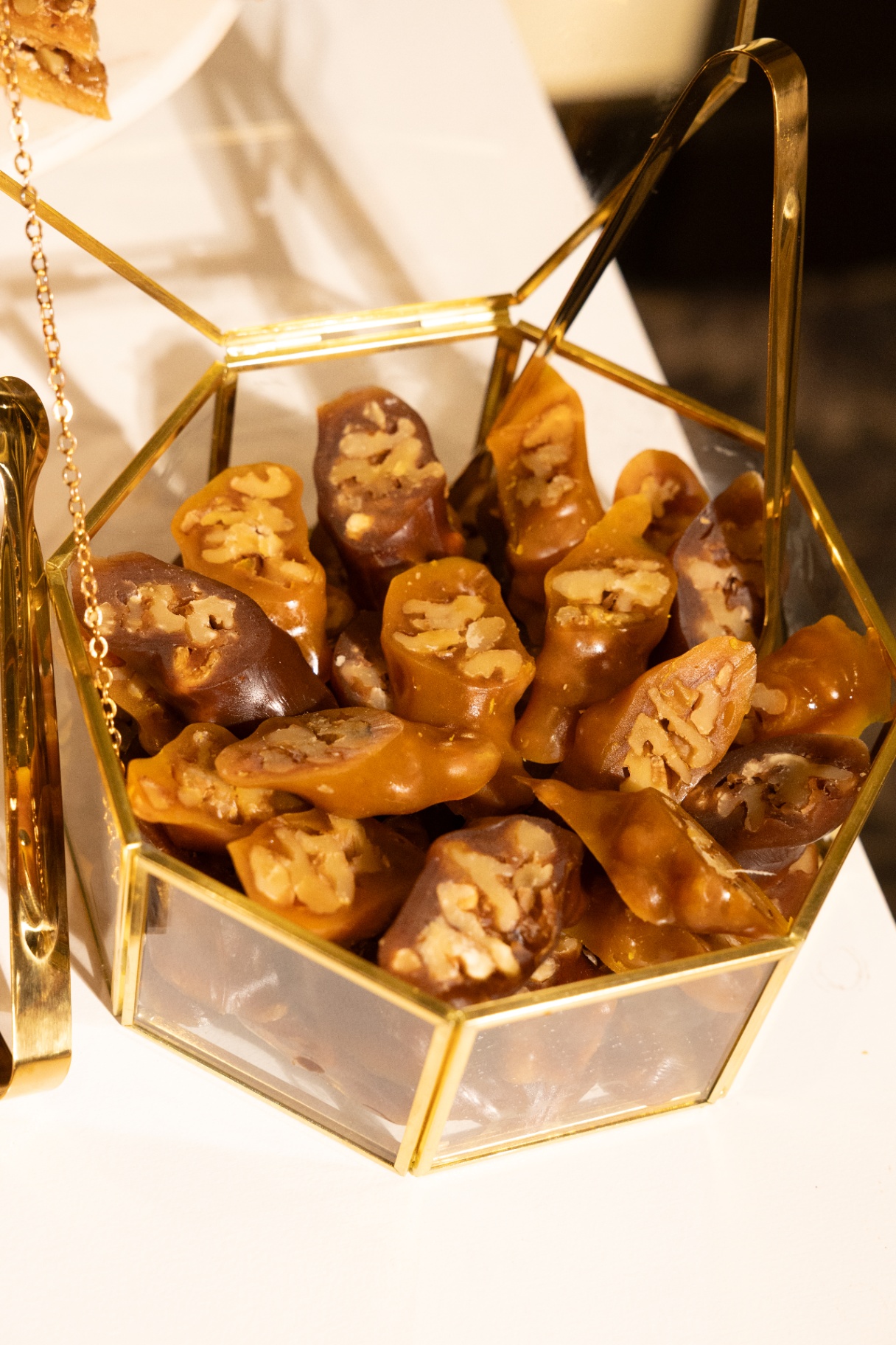Walnut-stuffed caramel dates in a gold geometric display box